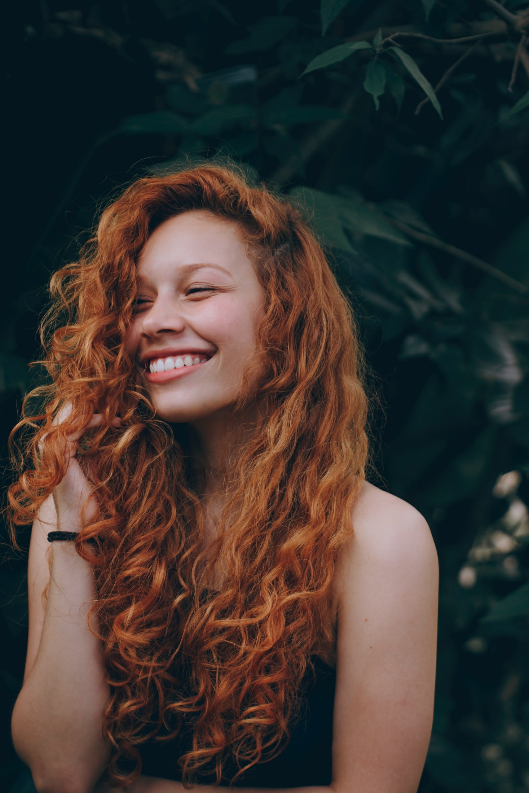 Femme aux cheveux longs et bouclés montrant le résultat d'une greffe de cheveux